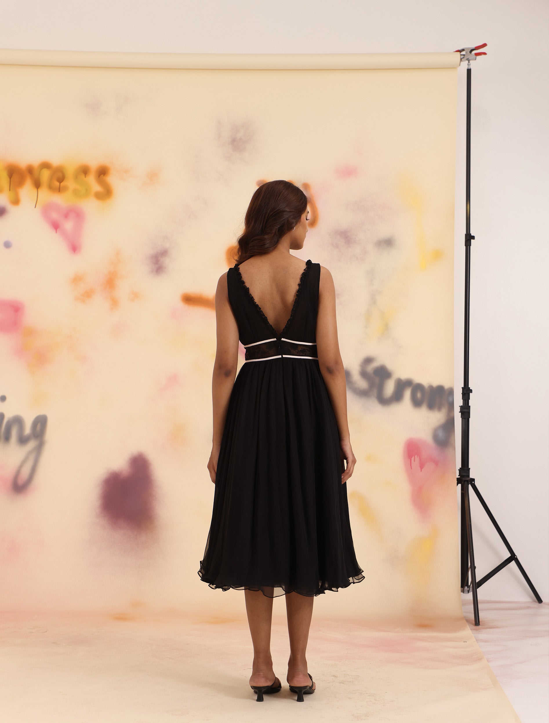 Full-length back view of black Ribbon-Tie Flared Midi Dress with flared gathered skirt