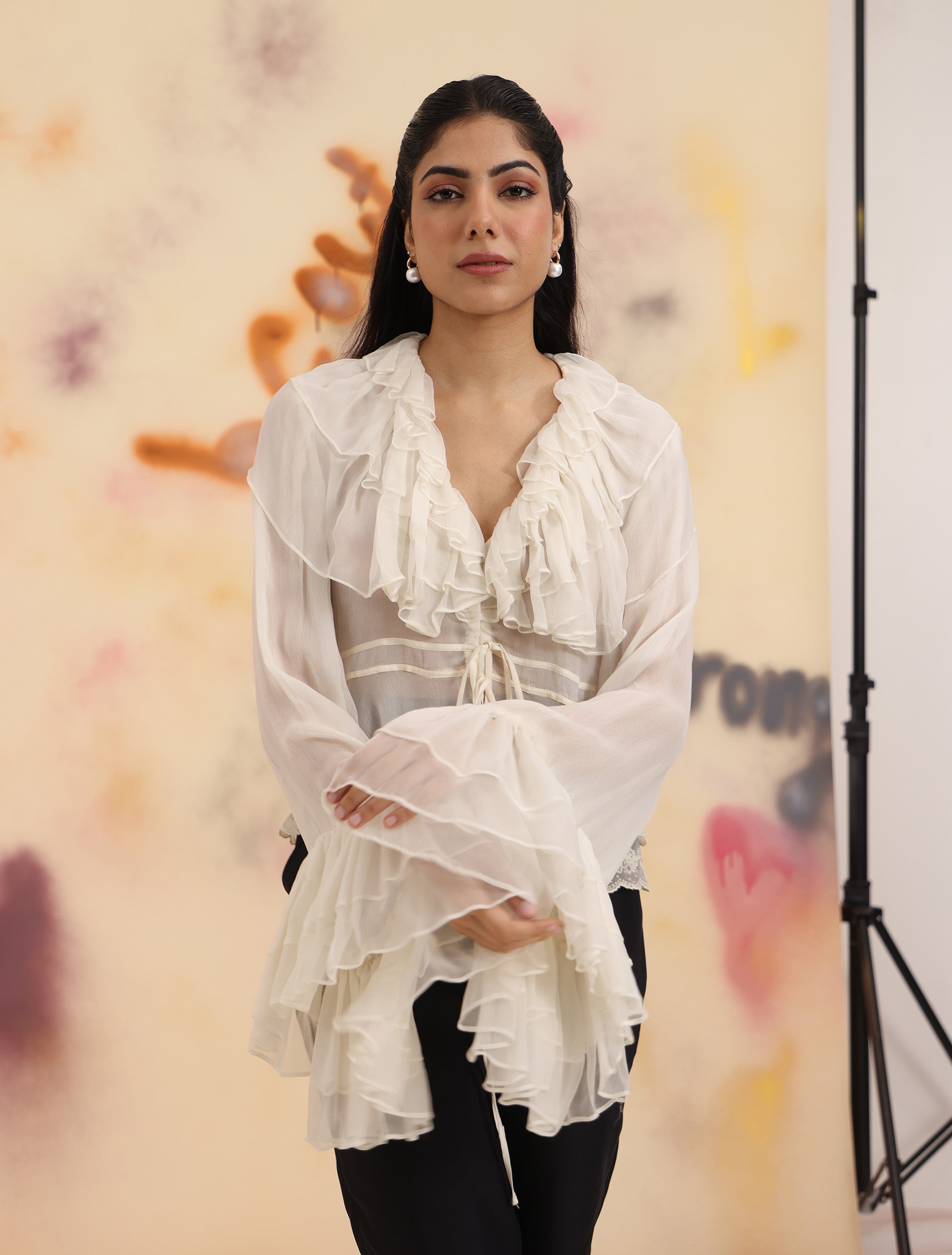 Sheer Ruffle Shirt - Cloud Dancer with cascading ruffle neckline and tie waist styled with black trousers
